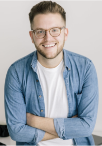 A man smiles while crossing his arms. 